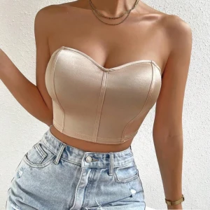 Champagnefärgad korsett topp från SHEIN  - Snygg croppad korsett topp i champagnefärgad satin med axelbandslös design och markerade sömmar framtill. Toppen har en tight passform. Aldrig använd!🥰