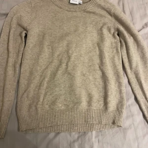 Beige stickad tröja från salt  - Snygg beige stickad tröja från salt med rund hals och ribbade muddar vid ärmslut och nederkant. Perfekt för lager-på-lager och enkel att matcha med jeans eller kjol. Mjuk och skön känsla, passar dig som gillar stilrena plagg.