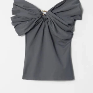 Other stories topp - Snygg grå topp med omlott-design och stora volanger över axlarna. Toppen är off shoulder och har en fyndig detalj fram. Bara använd en gång och säljer för att jag inte passar i den. Nypris 690kr💕💕