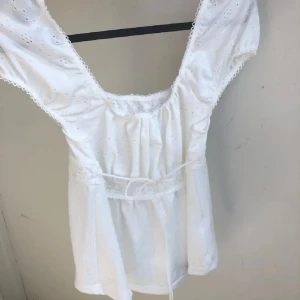 Vit blus med spets och snörning - Jätte gullig vit blus . Toppen har korta ärmar, söt knytning i midjan, den går att knyta i bak oxå om man vill de. Det är mjukt tunt tyg som är bekväm. Använd ca 2-3 gånger. (min kamera på telefonen är lite skum ibland men om du vill ha bättre bild kan det såklart fixas💕
