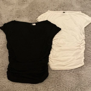 Svart och vit croppad topp från H&M Divided - Två croppade toppar från H&M Divided, en svart i storlek S och en vit i storlek XS. Båda har rund hals, ärmlös design och snygg rynkning i sidorna som ger en tight passform. Perfekt till jeans eller kjol för en clean och enkel look. Använda ett fåtal gånger och är i mycket bra skick.