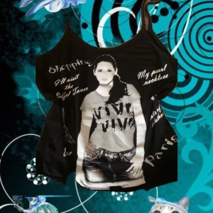 Svart linnetopp med Paris-tryck - Cool svart linnetopp med breda axelband och stort grafiskt tryck av en tjej i jeansshorts samt text som 'Shopping', 'Paris' och 'Eiffel Tower'. Toppen har en kontrast mellan svart och vitt och är perfekt för dig som gillar streetstyle och statement-plagg.