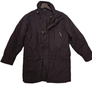 Svart Vinterjacka från Dubbster  - Svart vinterjacka med knäppning och dragkedja. Modellen är rymlig i passformen. Perfekt om du vill ha en tröja under. Jackan har hög krage och flera fickor framtill. Varm och skön för kyliga dagar 