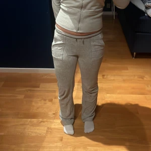 juicy couture byxor - Säljer ett par grå mjukisbyxor med normal passform och raka ben. Byxorna har snörning i midjan, två framfickor och två bakfickor med lock. Perfekta för chill dagar eller när du vill vara extra bekväm. Materialet är mjukt och stretchigt. Storlek xs men passar även s. Är dock super små fläckar på framsidan på byxorna men som ni ser på bilden syns dom knappt därav de billiga priset.