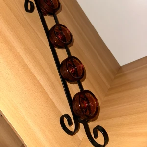 Ljusstake i smide med glasinsatser -  smidesjärn med fyra bruna glaslyktor. Perfekt för att skapa en mysig atmosfär i hemmet. Glasen är löstagbara och allt ser ut att vara i mycket gott skick utan synliga defekter eller slitage.Dekorativ ljusstake för värmeljus. Den har en smidesställning med plats för fyra glasinsatser i en varm färg.