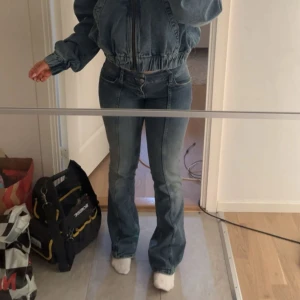 Blå bootcut jeans med hög midja - Snygga blå jeans med bootcut och låg midja. Jeansen har klassisk femficksdesign, dragkedja och knapp framtill. Materialet är jeans med en lätt tvättad look och passformen är normal med lite utsvängda ben. Perfekta för dig som gillar retrovibbar och vill ha en cool siluett.