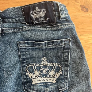 Rock & Republic jeans Victoria Beckham - Snygga blå jeans från Rock & Republic i samarbete med Victoria Beckham. Modellen har raka ben och coola broderade kronmotiv på bakfickorna. Klassisk femficksdesign, silverfärgade detaljer och slitningar för en trendig look.