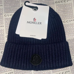 Moncler mörkblå black patch mössa  - Splitterny moncler vintermössa men svart märkte för exklusivtet.Medföljer monclerplastpåse för förvar när den inte används.  Unisex / Onesize finns i Göteborg. 