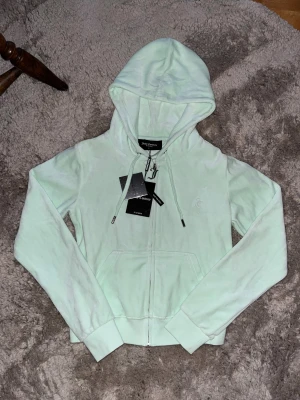 Mintgrön hoodie Juicy Couture S - Fräsch mintgrön hoodie från Juicy Couture i storlek S. Tröjan har huva med snörning, dragkedja med metall-J och två fickor framtill. Materialet är mjukt och bomullsrikt, perfekt för chill dagar. Diskret Juicy Couture-logga broderad på bröstet. Helt oanvänd och ska inte ha några defekter!💚🩵💚 