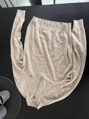 Beige half zip stickad tröja Morris  - Använd mindre än 5 gånger då den köptes för liten. Snygg beige stickad tröja från morris med half zip-dragkedja och diskret logga broderad. Tröjan har långärmad passform och ribbade muddar vid ärmslut och nederkant. Perfekt för lager-på-lager under hösten och vintern.
