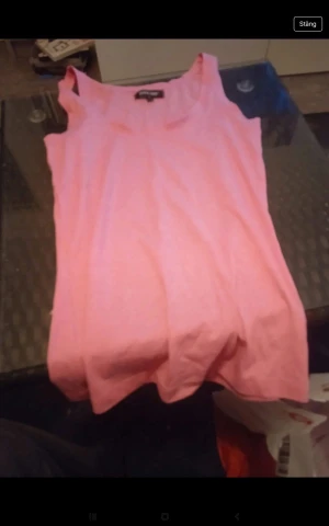 Rosa ärmlös linnetopp - Säljer en enkel och snygg rosa linnetopp med breda axelband. Toppen är ärmlös och har en rak passform, perfekt för varma dagar. Materialet känns mjukt och lätt mot huden.