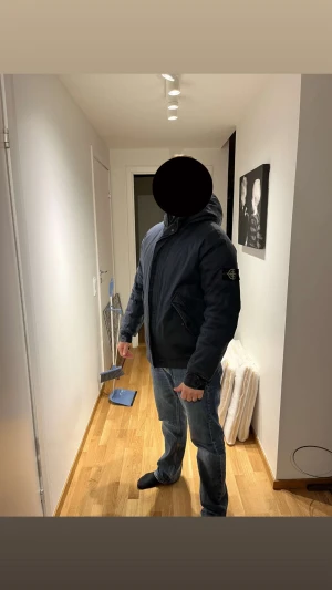 Svart pufferjacka från Stone Island - Säljer en svart pufferjacka från Stone Island med huva och ikonisk patch på vänster ärm. Jackan är tillverkad i performance cotton med Primaloft insulation, vilket gör den både lätt och varm. Den har dragkedja och knappar framtill samt två snedställda fickor med lock.