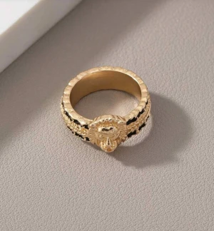 Guldfärgad ring med lejonhuvud - Cool ring i guldfärg med ett detaljerat lejonhuvud framtill. Ringen har svarta inslag längs bandet som ger en snygg kontrast och extra edge. Perfekt accessoar för dig som vill sticka ut och addera lite attitude till din stil.