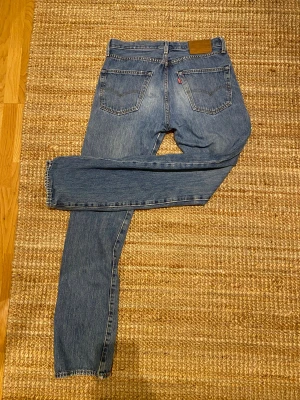 Levi's 501 Premium blå jeans - Säljer ett par klassiska Levi's 501 Premium jeans i blå tvätt. Modellen har rak passform, fem fickor och knappgylf. Jeansen är tillverkade i slitstarkt bomullsjeansmaterial. Stl