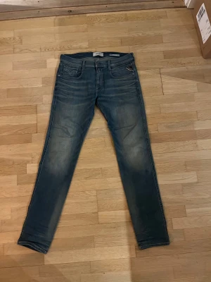 Replay Hyperflex blå jeans 31/34 - Snygga Replay Hyperflex jeans i blå tvätt med snygg wash och klassisk femficksdesign. Modellen har slim passform och stretchigt material som ger grym komfort. Perfekt för dig som gillar stilrena och moderna jeans med cool look.