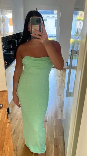 Mintgrön axelbandslös långklänning - Säljer en mintgrön axelbandslös långklänning med glittriga detaljer från OhPolly. Klänningen har en figurnära passform och är täckt av små pärlliknande dekorationer som ger en lyxig känsla. Perfekt för dig som vill sticka ut med en fräsch färg och snygg siluett. Klänningen är i storlek 12 som motsvarar storlek 40, endast använd en kväll i några timmar💚