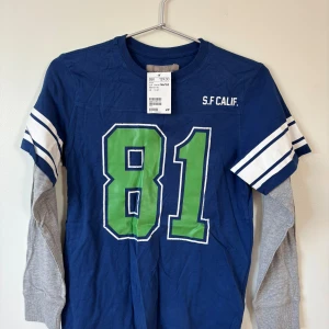  L.O.G.G. långärmad tröja - 146/152 Storlek - Blå långärmad tröja från L.O.G.G. i storleken 146/152. Tröjan har gråa långa ärmar under de blå korta ärmarna med vita och blå ränder. 