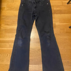 Svarta bootcut jeans - Svarta jeans med klassisk femficksdesign och bootcut-ben. Jeansen har låg  midja och är tillverkade i ett stretchigt denimtyg som ger en skön passform. Perfekta för dig som gillar en tidlös look med lite utsvängda ben.