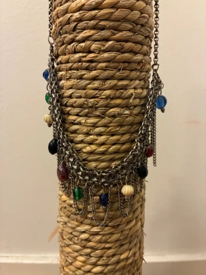 Chunky halsband med färgglada pärlor - Unikt chunky halsband i silverfärgad metall med flera kedjor och hängande pärlor i blått, grönt, svart, rött och beige. Kedjorna ger en cool lager-på-lager-effekt och pärlorna i olika färger gör halsbandet till en riktig statement piece.