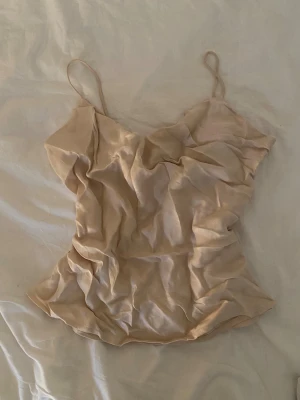 Beige/créme satinlinne från Zara - Jätte fin topp från Zara i crémefärg med dubbeltyg runt bröstet. Är praktiskttaget i nyskick men ifall man inte tycker om vikningarna går det att styrka bort😊