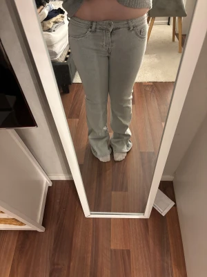 Grå bootcut jeans från H&M Divided - Snygga ljusgrå jeans från H&M Divided i bootcut-modell. De har klassisk femficksdesign, normal passform och är tillverkade i mjukt jeanstyg. Midjan är low waist och benen har en lätt utsvängd siluett. Perfekt för dig som gillar retrovibbar och stilren look. MIDJEMÅTT 79cm. INNERBENSLÄNGD 78cm