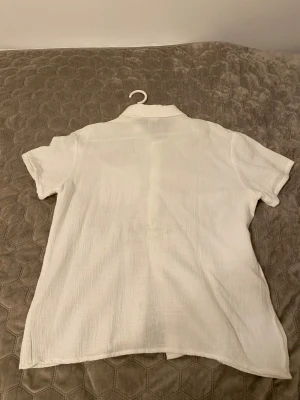 Vit kortärmad skjorta med knappar - Vit skjorta i luftig bomull med korta ärmar och klassisk krage. Skjortan har en bröstficka och snygga ljusa knappar framtill. Perfekt för varma dagar och enkel att styla till olika outfits. Jätte jätte bekväm också