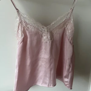 Ljusrosa siden-linnetopp med spets - Jättefint linne från H&M i storlek XS. Egentligen tänkt som en pyjamas men jag har använt det som en vanlig topp också💗 Detta är egentligen ett set men eftersom shortsen har några missfärgningar kommer jag endast ta betalt för linnet, du får alltså shortsen på köpet (om du vill! 🥰) Linnet är dock i jättebra skick