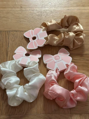 Satin scrunchies i tre färger - Tre snygga scrunchies i satin från Accessory, perfekta för att ge din frisyr extra glans. Färgerna är champagneguld, ljusrosa och vit. De är mjuka och skonsamma mot håret och har en glansig finish som ger en lyxig känsla. 19 each and 49 for tre pcs pm for preferred colors
