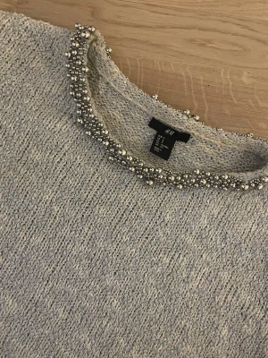 Stickad tröja med pärlor  - Säljer en grå stickad kortärmad med pärlor, storlek S men skulle säga att den passar mer XS. Super fin och bekväm, nästan aldrig använd.❤️ skriv dm om ni vill ha bild hur den ser ut på❤️