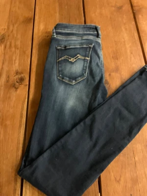 Replay skinny jeans blå - Snygga Replay jeans i mörkblå tvätt med slitningar och kontrastsömmar på bakfickorna. Modellen är klassisk femficksdesign. Jeansen är tillverkade i stretchigt denim för en tight passform och har knapp och dragkedja framtill.