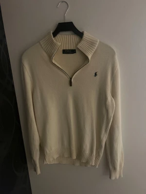 Beige stickad half zip från Polo Ralph Lauren - Snygg beige stickad tröja från Polo Ralph Lauren med half zip. Storlek S . Är trasig löngst ut på armen på vänster sidan.