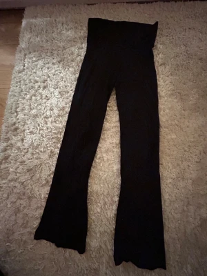 Svarta bootcut byxor från Gina Tricot - Säljer ett par svarta bootcut byxor från Gina Tricot med hög midja. Byxorna har en mjuk och stretchig känsla, perfekta för dig som gillar bekväma och stilrena plagg. Passar dig som vill ha en snygg siluett och gillar klassisk svart.