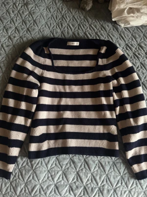 Randig stickad tröja från MNG - Säljer en ribbstickad tröja från MNG med breda marinblå och beige ränder. Tröjan har fyrkantig ringning, lång ärm och är i ett mjukt stickat material. I fint skick