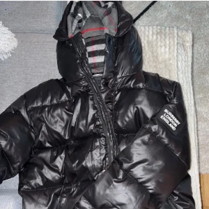Svart Burberry Vinterjacka BYTES? - Säljer en svart pufferjacka från Burberry med huva och klassiskt rutigt foder. Byter gärna mot någon monclerjacka
