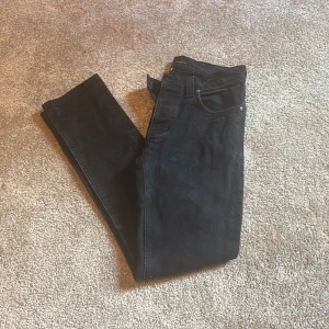 Mörkblåa jeans från Nudie Jeans, 31/32 - Säljer ett par mörkblåa jeans från Nudie Jeans i modellen 31/32. Jeansen är tillverkade i ekologisk bomull och har klassisk femficksdesign. Snygg rak passform och stilren look som funkar till det mesta. Perfekta om du gillar mörkblåa jeans med enkel vibe. Nyskick