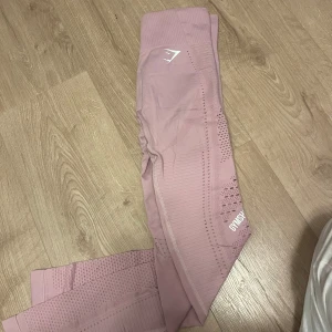 Rosa seamless leggings från Gymshark - Säljer ett par ljusrosa seamless leggings från Gymshark med hög midja. Tightsen har håldetaljer längs benen. Logga på benet och vid höften som inte alls är slitna! Har klippt av lappen i, men skulle säga ahh de passar någon som vanligtvis är S/M. Superstretchiga💞💕