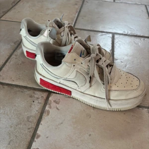 Nike Air Force 1 Shadow beige/röd - Beiga Nike Air Force i storlek 38, några defekter som slitage på skosnöre samt insida häl. Köpta för 1299kr