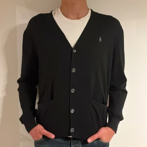 Polo Ralph lauren cardigan - En stickad cardigan från polo Ralph lauren i storlek L (passar M/L). Nypris: 2100kr. Vårt pris: 499kr. Modellen är 190cm och väger 81kg. Hör av er vid frågor/fler bilder!