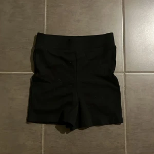 Svarta ribbade shorts från H&M XS - Svarta shorts från H&M i storlek XS. De är ribbade och har en hög midja som sitter skönt och tight. Perfekta för sommaren eller till träning. Materialet är stretchigt och mjukt, vilket gör dem riktigt bekväma att ha på sig.