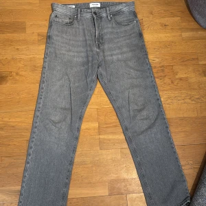 Grå jeans från Jack & Jones, straight fit - Säljer ett par grå jeans från Jack & Jones i klassisk straight fit. Jeansen har fem fickor, normal passform och är tillverkade i ett mjukt bomullsmaterial. Perfekta för dig som gillar en enkel och stilren look.