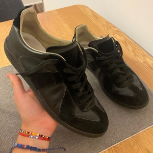 Maison margiela skor - Säljer dessa maison margiela skor i storlek 43. Jag har köpt skorna second hand och har fått kollat och man ser att de är äkta. Man kan bland annat se det på sulan som visas på bilden. Tyvärr har jag inte ”riktigt” bevis på att skorna är äkta så man få ha det i åtanke när man köper. Jag kommer därför att sälja dem för bra pris.  Skorna är i väldigt bra skick. Endast skorna ingår. Köper man så har man köpt. Ingen retur