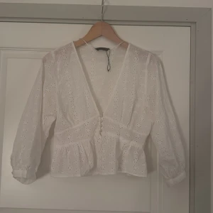Spets blus från Zara  - Superfin vit blus med v-ringning och broderade blommor. Blusen har knappar framtill, volang nertill och långa ärmar med lätt puff. Nästan ny skick då jag använt den endast 1 gång 