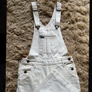 Crèmevita Lee hängselbyxor i jeans - Säljer ett par crémevita hängselbyxor från Lee. De har raka ben, axelband med justerbara spännen och fickor fram och bak. Fint skick! Bilderna är lite suddiga då bilderna blev för inzoomat i orginalformat, men kan skicka bilderna i orginalformat ifall man önskar det☺️