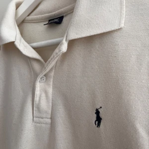 Ralph Lauren pike  - Säljer nu en riktigt stilig Ralph Lauren piké, piken är 100% bomull och i färgen beige/vit. 💯Den passar till allt under sommaren och vintern🙌. Inget tydligt slitage men man märker att den har används. Priset är hugget i sten men hör av er vid andra tankar och frågor.😀               Skick:6/10👍                                       Ny pris:1499kr🌩️                               Mitt pris:359kr✅