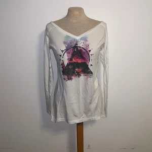 Vit långärmad tröja från Roxy - Vit långärmad tröja från Roxy med v-ringning och färgstarkt grafiskt tryck framtill i lila, rosa och svart. 