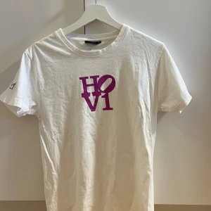 Vit unik Hov1 t-shirt  - Vit t shirt från hov1 med lila tryck, knappt använd. Storlek S. Kom med bud eller köp direkt för 500 kr