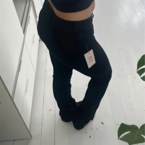 Svarta bootcut jeans från Nelly - Säljer ett par svarta bootcut jeans från Nelly i modellen Low Waist Perfect Bootcut. Byxorna har låg midja och klassisk bootcut-passform som sitter snyggt över höfterna och släpper ut vid benen. Materialet är jeans och färgen är helsvart.