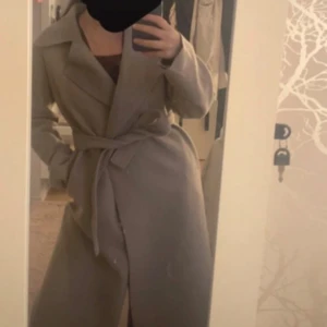 Beige tunn kappa från Nelly - Så snygg tunn beige kappa från nelly. Den lägger sig mycket fint på kroppen då den inte är så tung och tjock, perfekt till denna säsong! Bra skick inga skador. Stor i storlek 