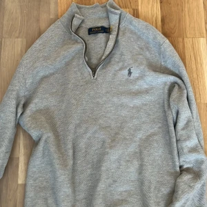 Grå half zip tröja från Polo Ralph Lauren - Säljer en stilren grå tröja från Polo Ralph Lauren. Den har en dragkedja vid halsen och det klassiska logotypbroderiet på bröstet. Perfekt för både vardag och lite finare tillfällen. Tröjan är i bra skick och passar perfekt till höst och vår.