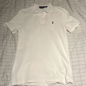 Vit slim fit piké från Polo Ralph Lauren XL (barnstorlek) - Vit pikétröja från Polo Ralph Lauren i slim fit-modell. Klassisk krage, två knappar och broderad marinblå logga på bröstet. Tillverkad i bomull med korta ärmar och stilren design som alltid funkar. Perfekt för dig som gillar clean och enkel stil. (Jag är 175cm lång och den passar perfekt på mig)